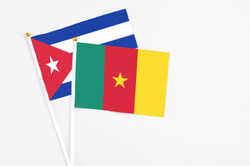 Cameroon and Cuba stick flags on white background. High quality fabric, miniature national flag. Peaceful global concept.White floor for copy space.