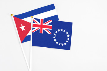 Fototapeta premium Cook Islands and Cuba stick flags on white background. High quality fabric, miniature national flag. Peaceful global concept.White floor for copy space.