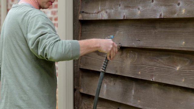 Man installs outdoor faucet cover to protect pipes during cold weather