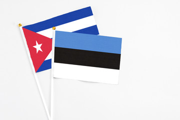 Estonia and Cuba stick flags on white background. High quality fabric, miniature national flag. Peaceful global concept.White floor for copy space.