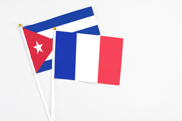 France and Cuba stick flags on white background. High quality fabric, miniature national flag. Peaceful global concept.White floor for copy space.