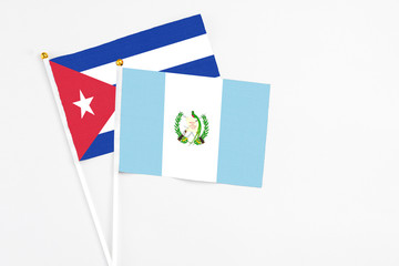 Guatemala and Cuba stick flags on white background. High quality fabric, miniature national flag. Peaceful global concept.White floor for copy space.