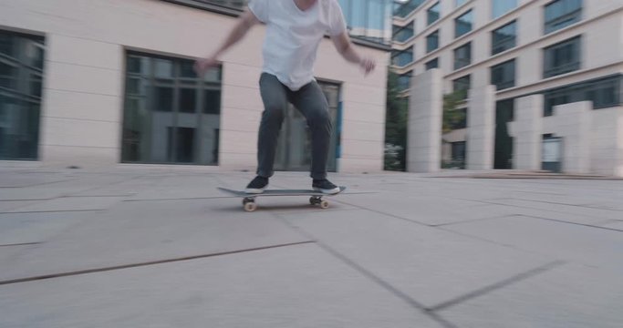 skateboarder getting filmed jumping ollie flip trick in super slow motion at business buildings