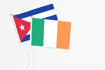 Ireland and Cuba stick flags on white background. High quality fabric, miniature national flag. Peaceful global concept.White floor for copy space.
