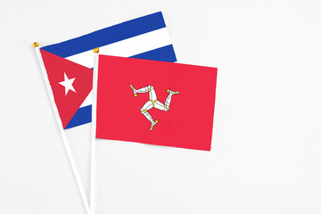 Isle Of Man and Cuba stick flags on white background. High quality fabric, miniature national flag. Peaceful global concept.White floor for copy space.
