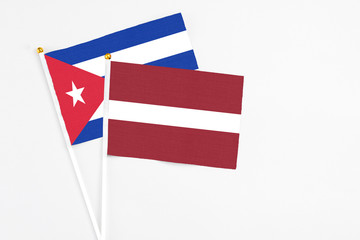 Latvia and Cuba stick flags on white background. High quality fabric, miniature national flag. Peaceful global concept.White floor for copy space.