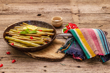 Baked green bean in pan with sesame seeds, pomegranate, mint and lemon