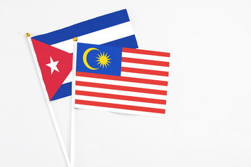 Malaysia and Cuba stick flags on white background. High quality fabric, miniature national flag. Peaceful global concept.White floor for copy space.