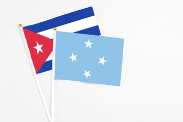 Micronesia and Cuba stick flags on white background. High quality fabric, miniature national flag. Peaceful global concept.White floor for copy space.