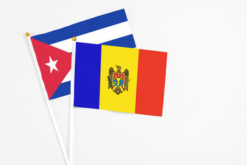 Moldova and Cuba stick flags on white background. High quality fabric, miniature national flag. Peaceful global concept.White floor for copy space.