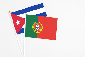 Portugal and Cuba stick flags on white background. High quality fabric, miniature national flag. Peaceful global concept.White floor for copy space.