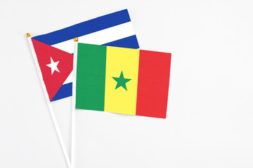 Senegal and Cuba stick flags on white background. High quality fabric, miniature national flag. Peaceful global concept.White floor for copy space.