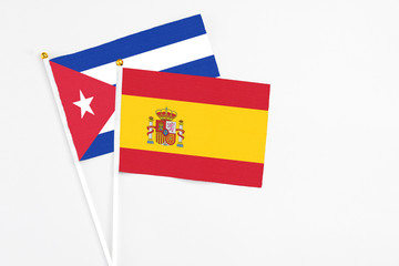 Spain and Cuba stick flags on white background. High quality fabric, miniature national flag. Peaceful global concept.White floor for copy space.