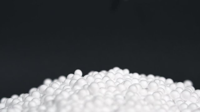 White round polystyrene packaging material drop from injection machine in slow motion, modern foam bead ball decoration cause global warming from chemical waste