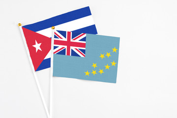 Fototapeta premium Tuvalu and Cuba stick flags on white background. High quality fabric, miniature national flag. Peaceful global concept.White floor for copy space.