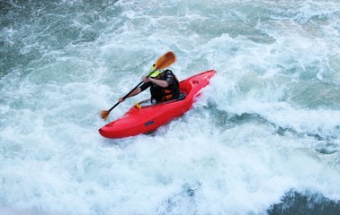 Fototapeta na wymiar Man sailing in a kayak on a whitewater mountain river