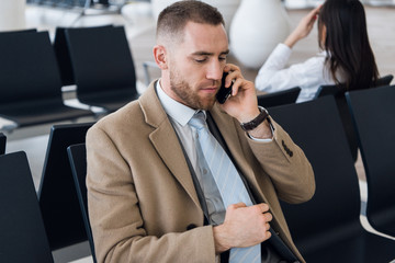 Man on smart phone - young business man in airport. Businessman using smartphone inside office building or airport.