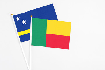 Benin and Curacao stick flags on white background. High quality fabric, miniature national flag. Peaceful global concept.White floor for copy space.