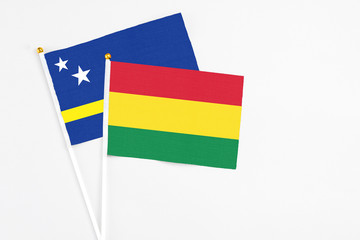 Bolivia and Curacao stick flags on white background. High quality fabric, miniature national flag. Peaceful global concept.White floor for copy space.