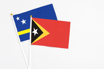East Timor and Curacao stick flags on white background. High quality fabric, miniature national flag. Peaceful global concept.White floor for copy space.