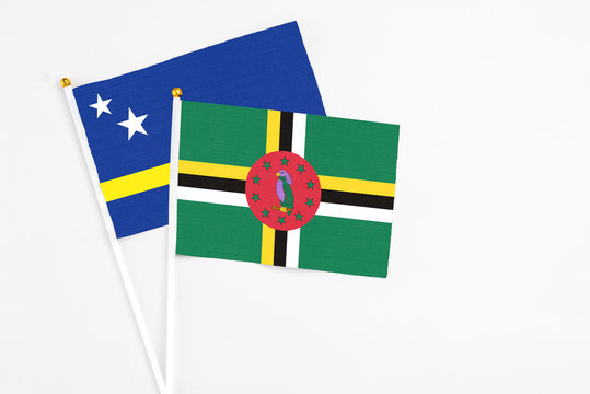 Dominica and Curacao stick flags on white background. High quality fabric, miniature national flag. Peaceful global concept.White floor for copy space.