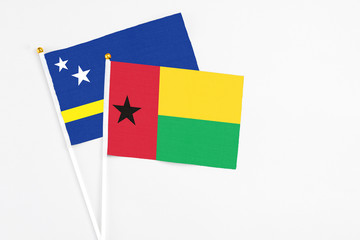 Guinea Bissau and Curacao stick flags on white background. High quality fabric, miniature national flag. Peaceful global concept.White floor for copy space.