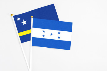 Honduras and Curacao stick flags on white background. High quality fabric, miniature national flag. Peaceful global concept.White floor for copy space.