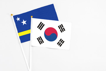 South Korea and Curacao stick flags on white background. High quality fabric, miniature national flag. Peaceful global concept.White floor for copy space.