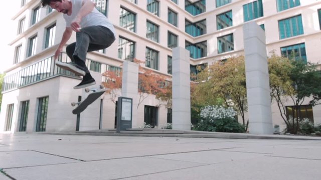 skateboarder doing flip trick in super slow motion at business buildings