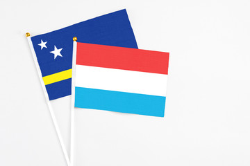 Luxembourg and Curacao stick flags on white background. High quality fabric, miniature national flag. Peaceful global concept.White floor for copy space.