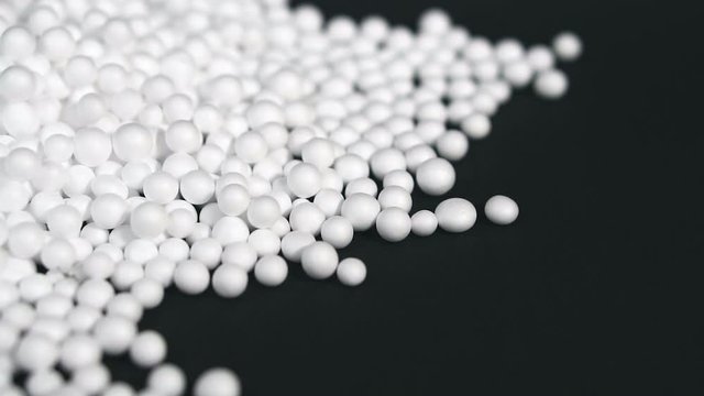 White round polystyrene packaging material drop from injection machine in slow motion, modern foam bead ball decoration cause global warming from chemical waste