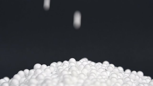 White round polystyrene packaging material drop from injection machine in slow motion, modern foam bead ball decoration cause global warming from chemical waste
