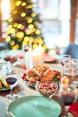 Setting of christmas table on festive holidays, full of traditional food with turky and delicious meals around the tree lights and decoration