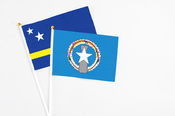 Northern Mariana Islands and Curacao stick flags on white background. High quality fabric, miniature national flag. Peaceful global concept.White floor for copy space.
