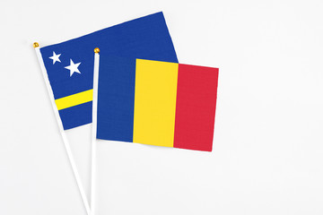 Romania and Curacao stick flags on white background. High quality fabric, miniature national flag. Peaceful global concept.White floor for copy space.