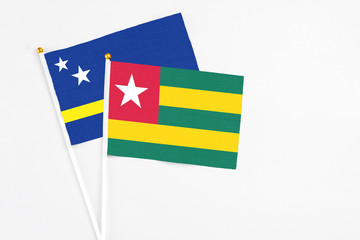 Togo and Curacao stick flags on white background. High quality fabric, miniature national flag. Peaceful global concept.White floor for copy space.