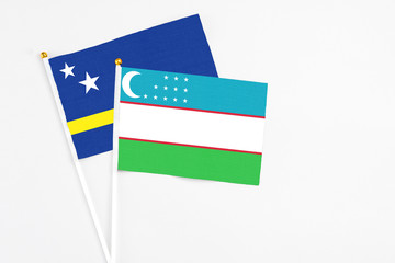 Uzbekistan and Curacao stick flags on white background. High quality fabric, miniature national flag. Peaceful global concept.White floor for copy space.