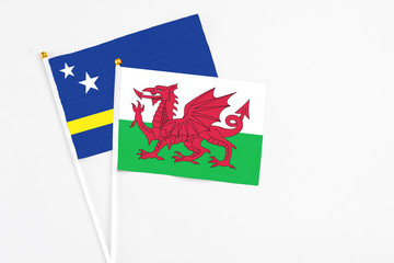 Wales and Curacao stick flags on white background. High quality fabric, miniature national flag. Peaceful global concept.White floor for copy space.
