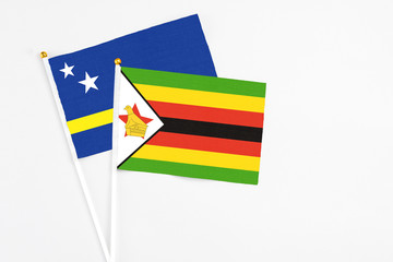 Zimbabwe and Curacao stick flags on white background. High quality fabric, miniature national flag. Peaceful global concept.White floor for copy space.