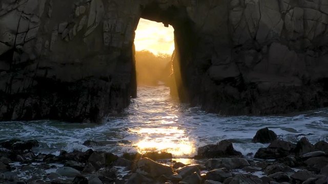 Orang and Teal complimentary colors naturally appear at this scenic location as the ocean waves crash through the large rocky sea stack in slow motion outside of Big Sur California, USA.