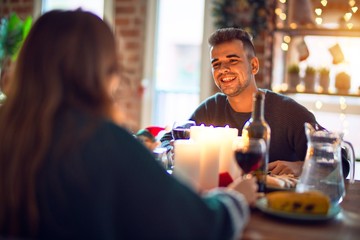 Young beautiful couple smiling happy and confident. Eating food celebrating christmas at home