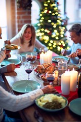Family and friends dining at home celebrating christmas eve with traditional food and decoration, all sitting on the table together
