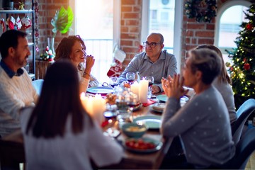 Family and friends dining at home celebrating christmas eve with traditional food and decoration, all sitting on the table together