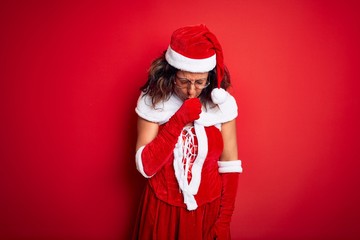 Middle age beautiful woman wearing Santa Claus costume over isolated red background feeling unwell and coughing as symptom for cold or bronchitis. Healthcare concept.