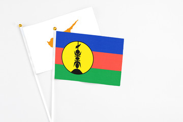 New Caledonia and Cyprus stick flags on white background. High quality fabric, miniature national flag. Peaceful global concept.White floor for copy space.
