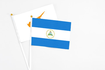 Nicaragua and Cyprus stick flags on white background. High quality fabric, miniature national flag. Peaceful global concept.White floor for copy space.