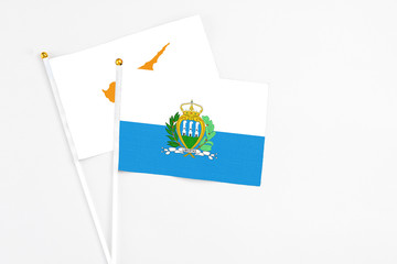 San Marino and Cyprus stick flags on white background. High quality fabric, miniature national flag. Peaceful global concept.White floor for copy space.