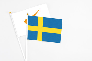 Sweden and Cyprus stick flags on white background. High quality fabric, miniature national flag. Peaceful global concept.White floor for copy space.