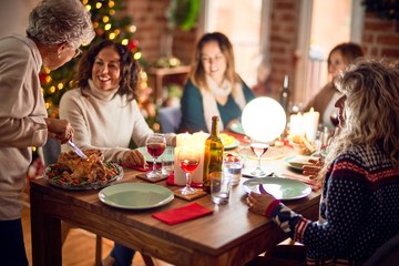 Beautiful group of women smiling happy and confident. Carving roasted turkey celebrating christmas at home