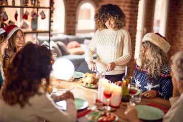 Beautiful group of women smiling happy and confident. Carving roasted turkey celebrating christmas at home